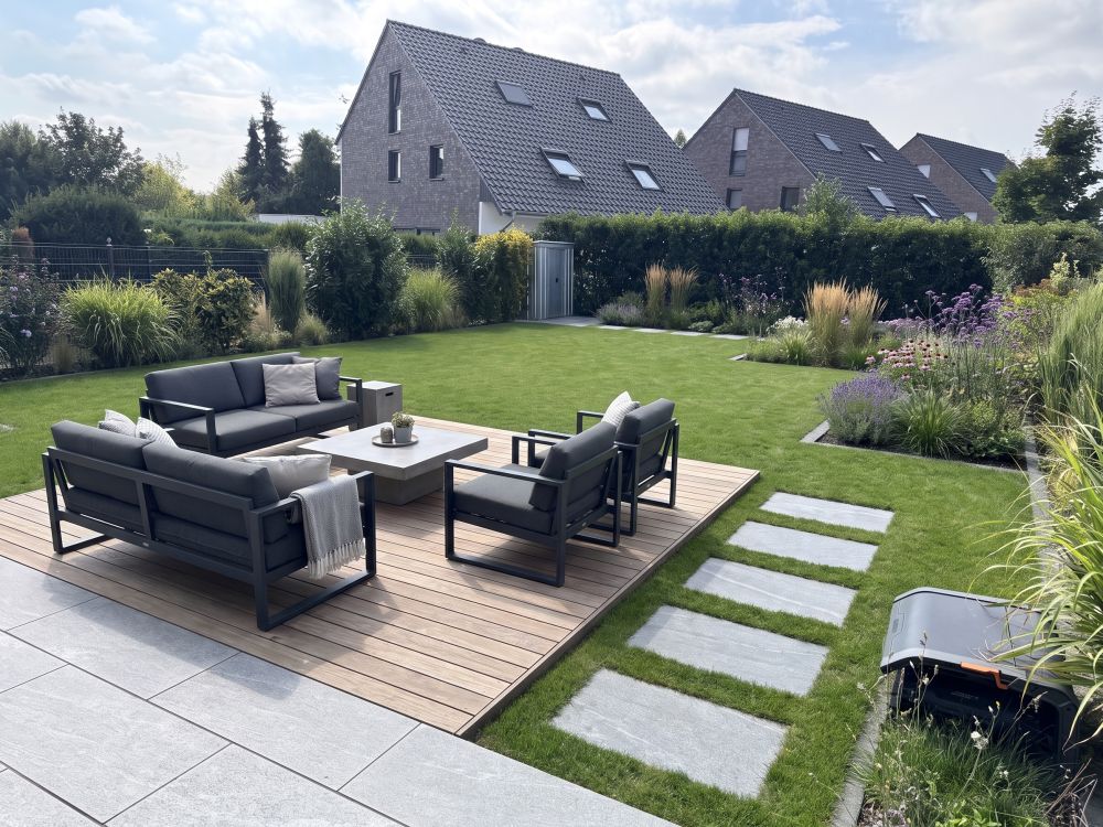 Garten mit Holzterrasse, Lounge-Möbeln und angelegten Beeten